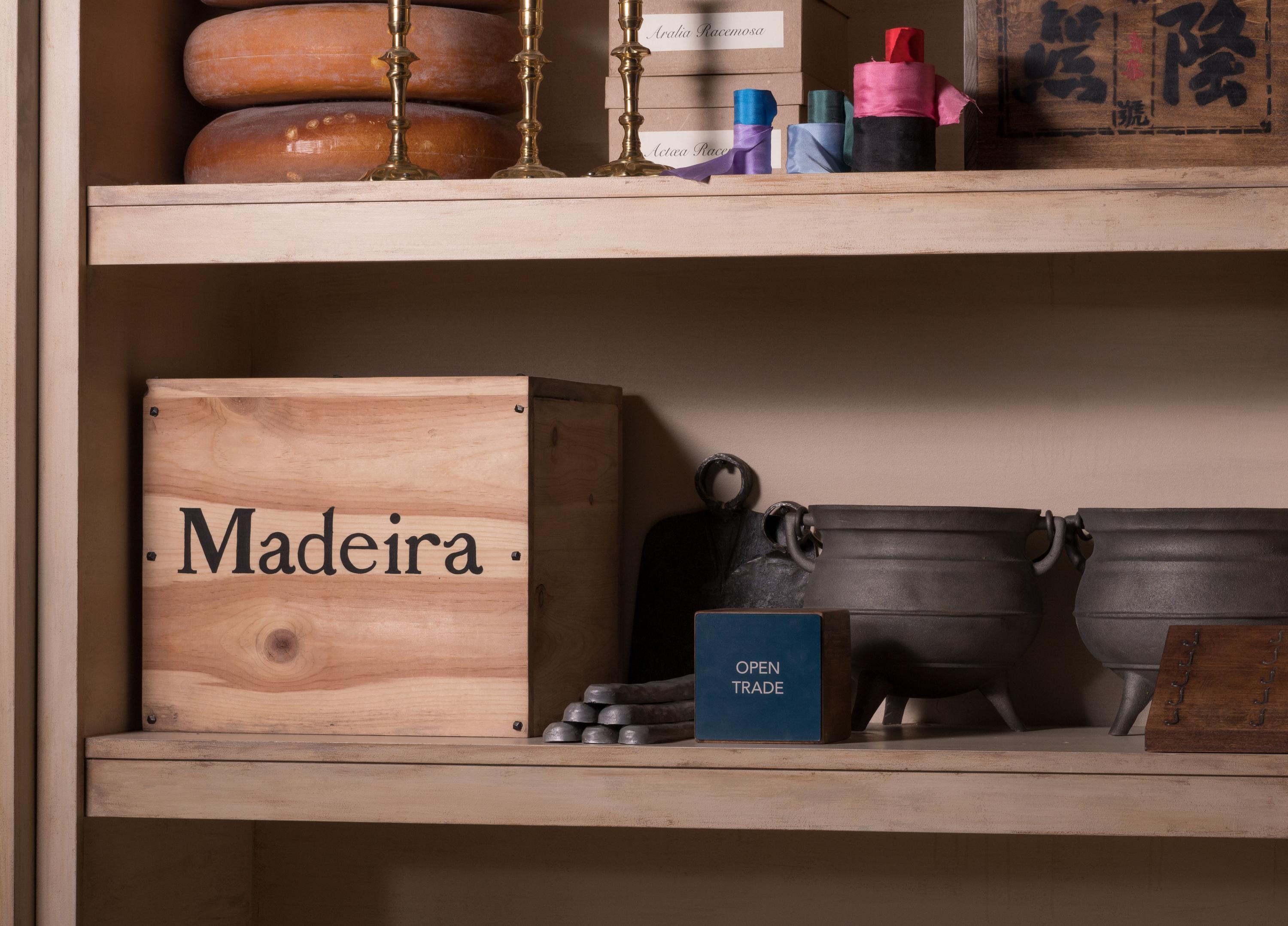 A wooden box labeled Madeira and pewter pots on wooden shelves