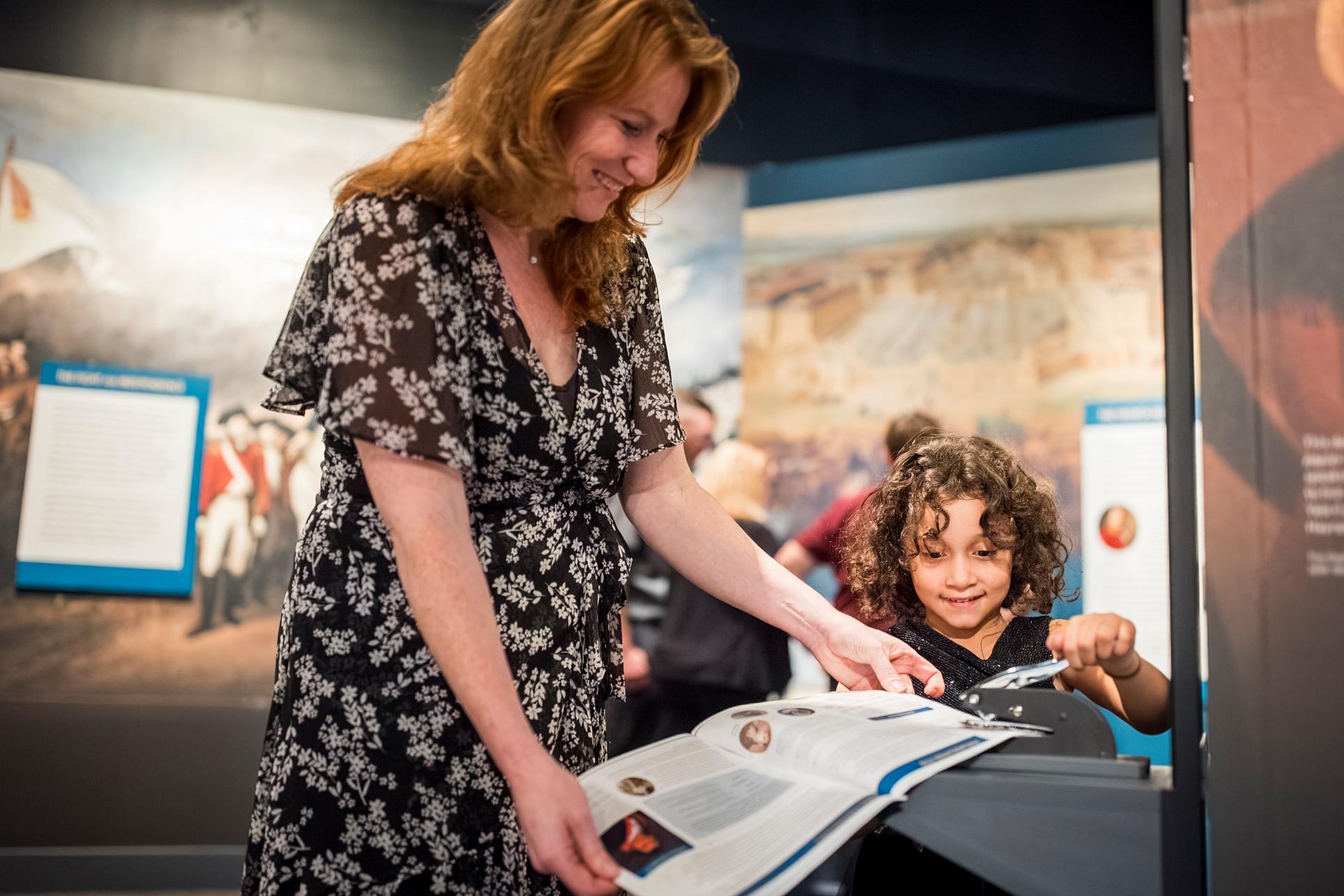 A woman and child stamp a family guide in the exhibition