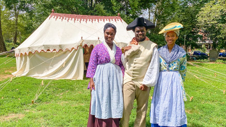 Three students from the Museum's Living History Youth Summer Institute pose for a photo in from the Museum's recreated George Washington's tent in Clark Park.