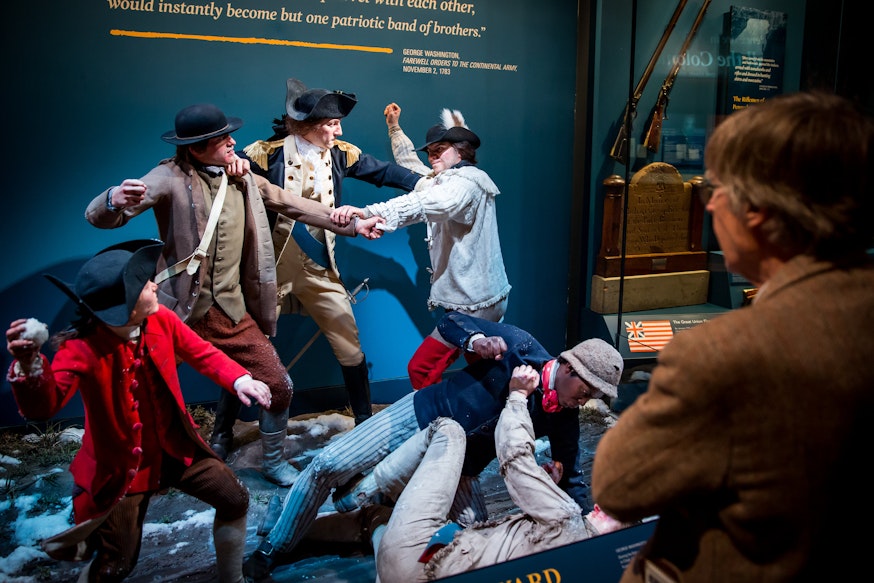 A visitor looks at a tableau scene depicting George Washington breaking up a fight among his troops in Harvard Yard.