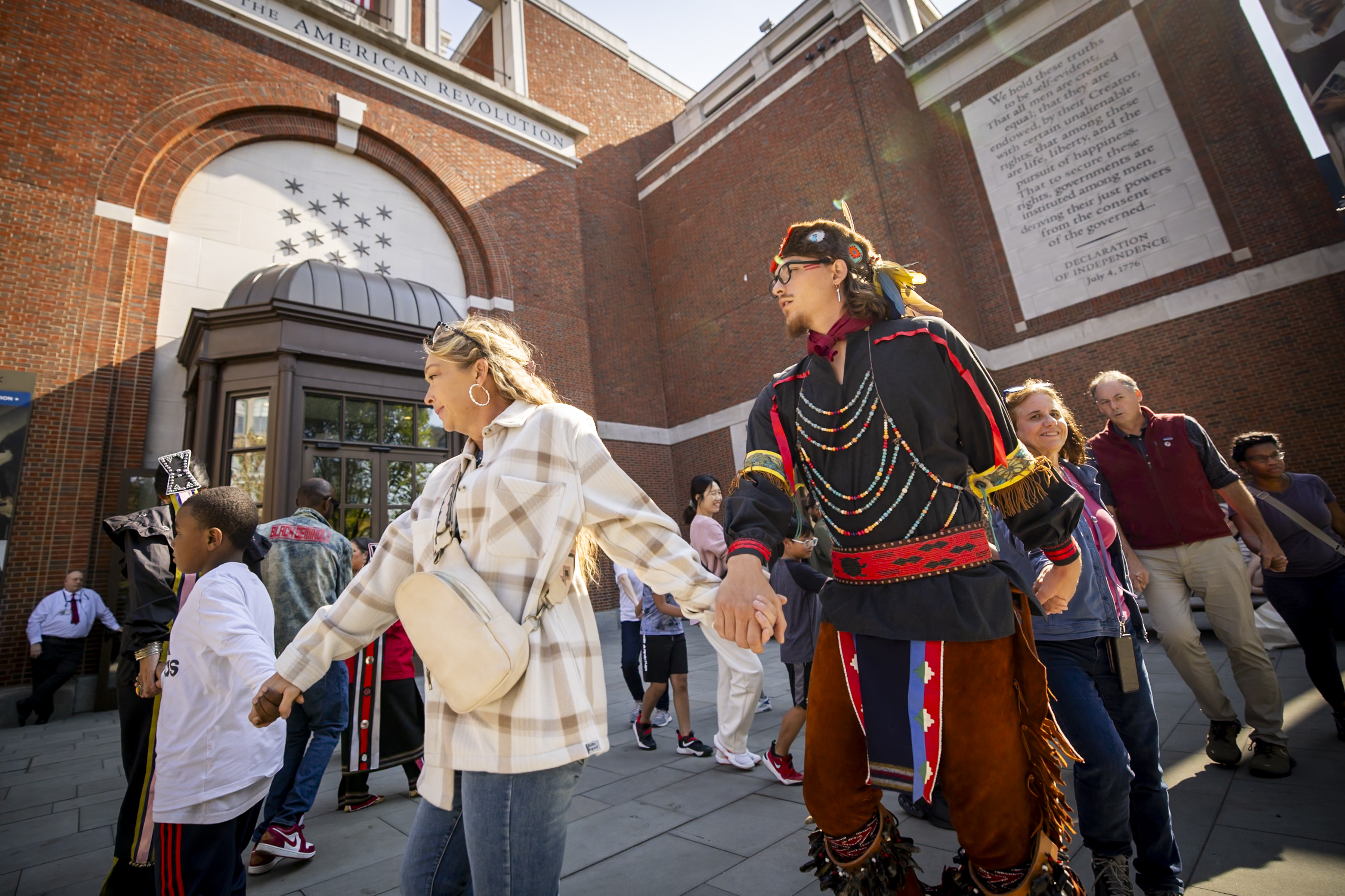 Man, women, and children dancing in circle