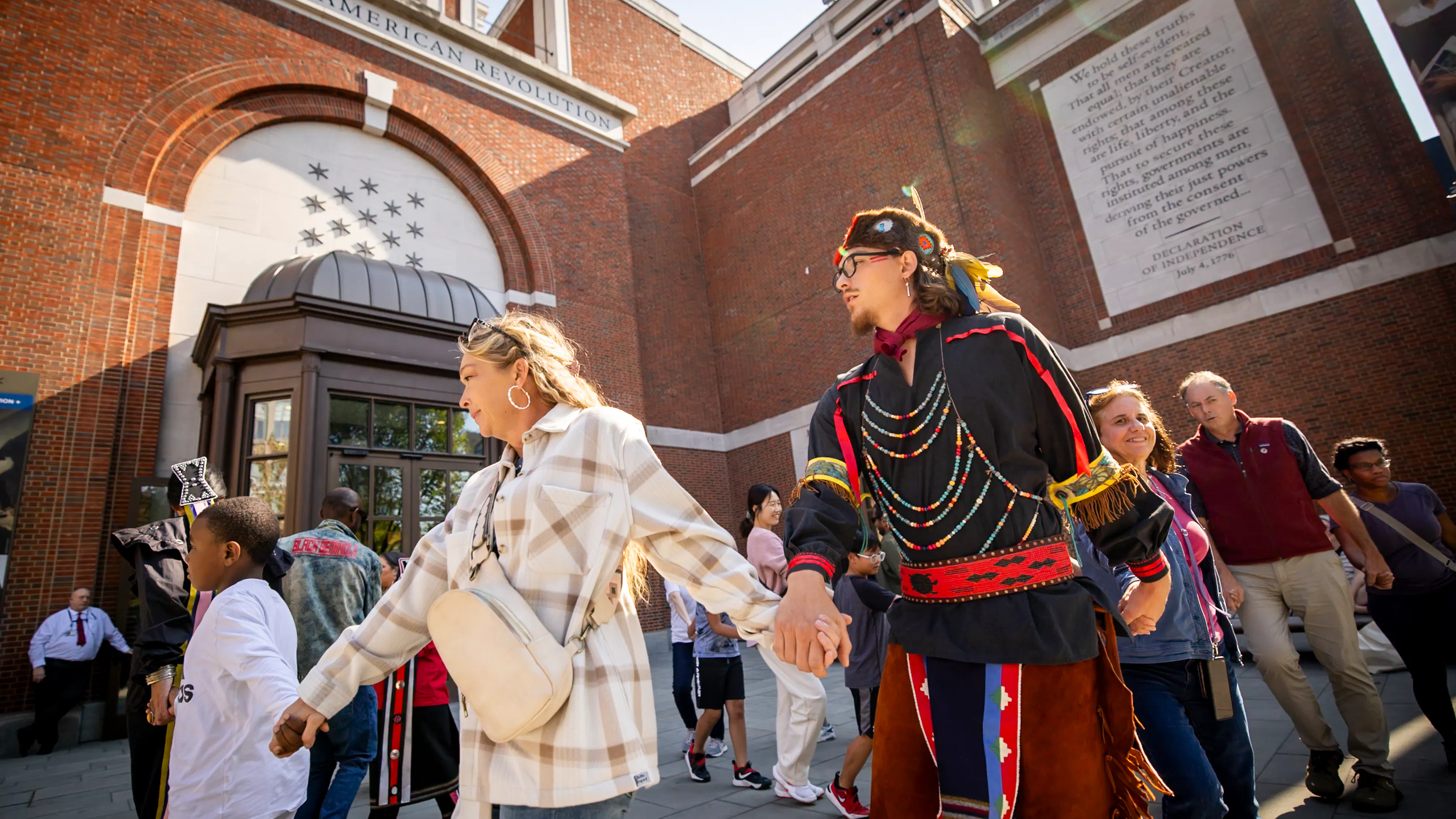 Man, women, and children dancing in circle