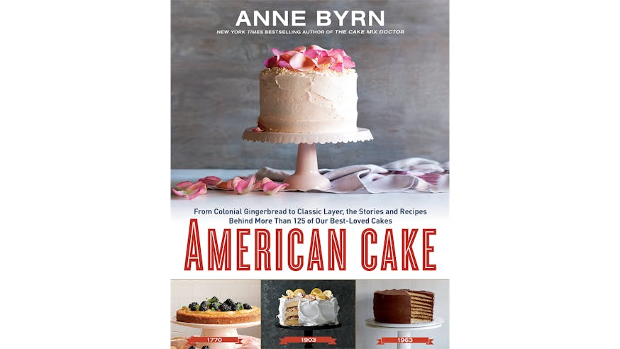 This image depicts the book cover of American Cake by Anne Byrn. The book cover shows a white frosted cake with pink rose petals on top. The cake sits on a white cake stand with more petals surrounding the right side of the stand. Below this image is the title of the book. Below the title of the book are three smaller photographs of cakes dated 1770, 1903, and 1963.