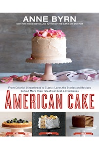 This image depicts the book cover of American Cake by Anne Byrn. The book cover shows a white frosted cake with pink rose petals on top. The cake sits on a white cake stand with more petals surrounding the right side of the stand. Below this image is the title of the book. Below the title of the book are three smaller photographs of cakes dated 1770, 1903, and 1963.