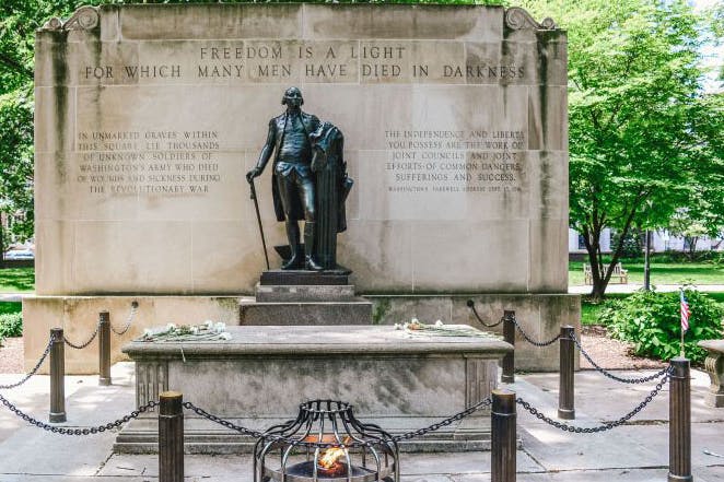 The Tomb of the Unknown Revolutionary War Soldier with a statue of George Washington in Washington Square Park in Philadelphia.