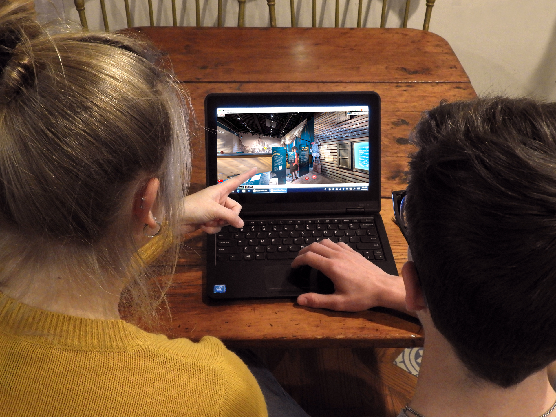 Two people look at a computer with the Timeline of the American Revolution on the screen