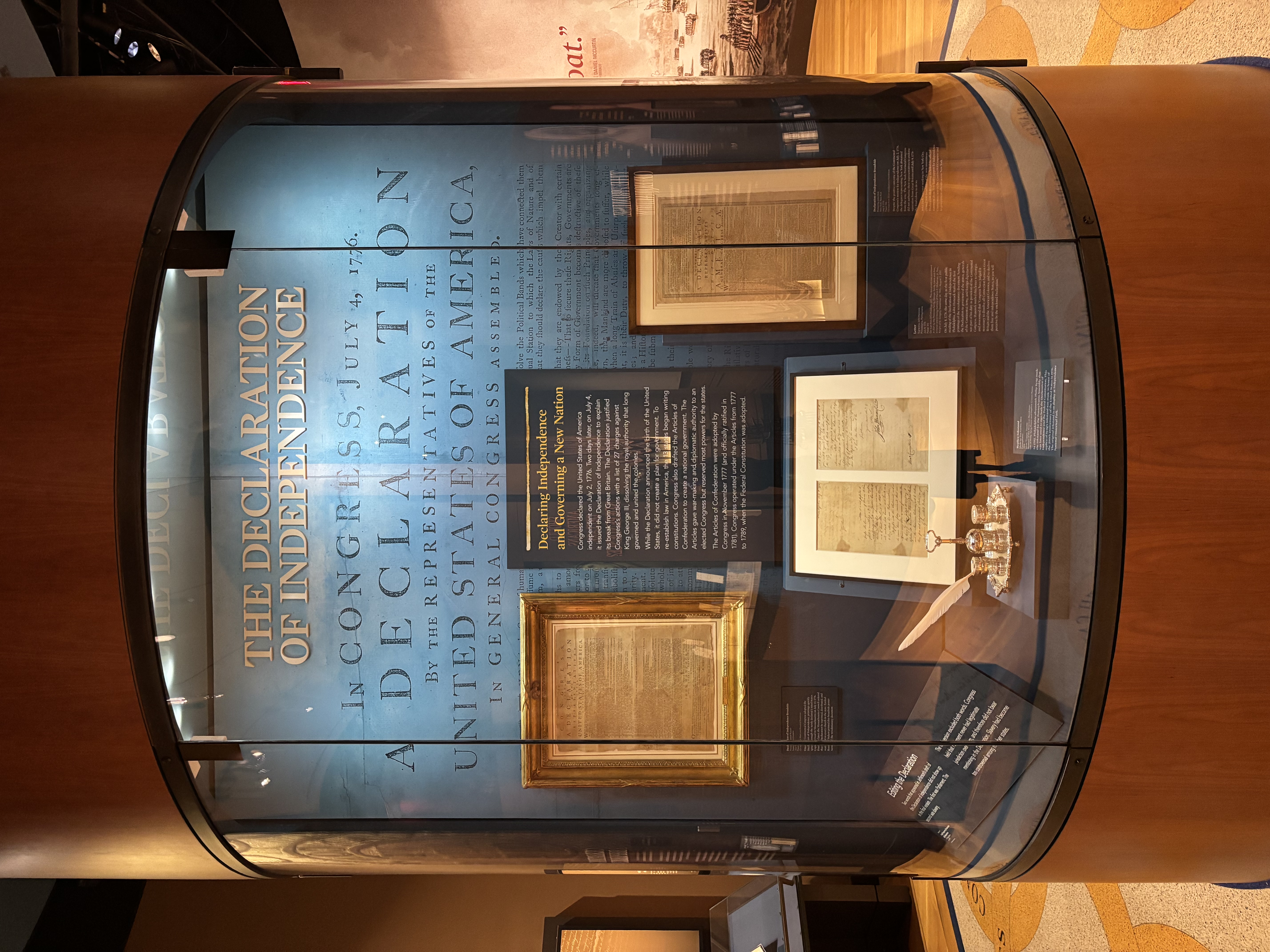 A display case with multiple framed documents and a silver inkstand