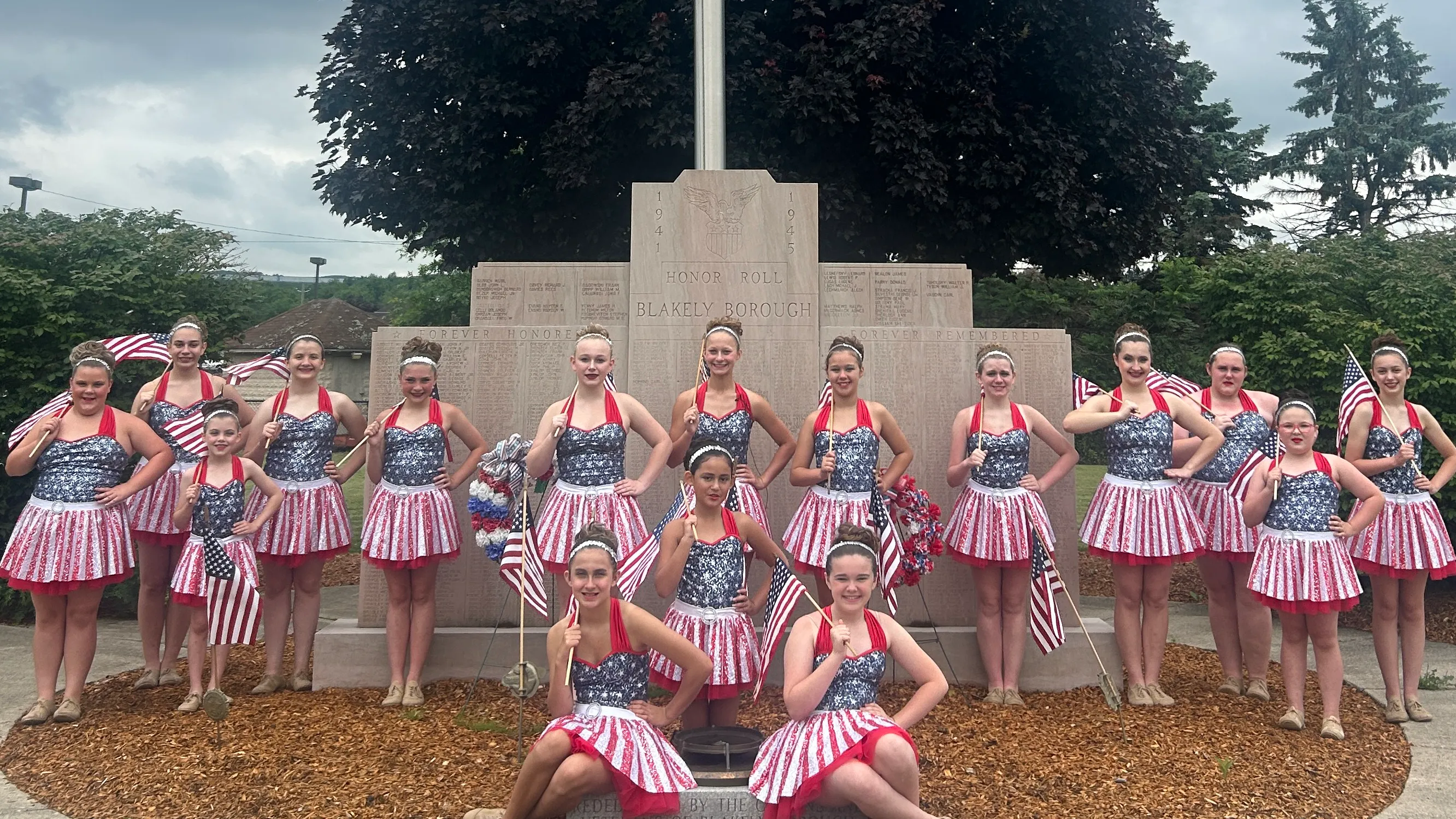 A group of young women pose in red, white, and blue costumes