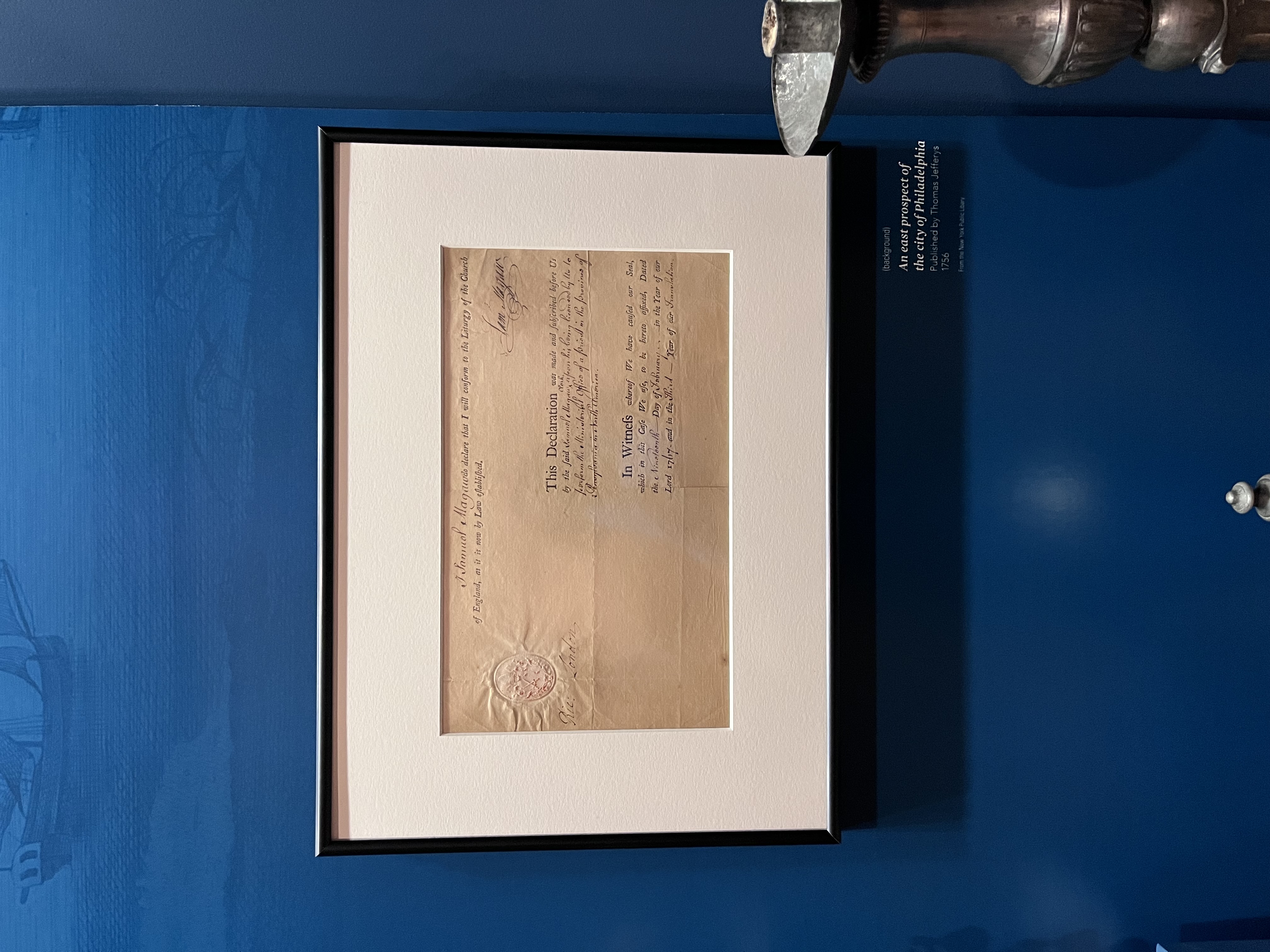 An 18th century document framed and hanging on a blue wall