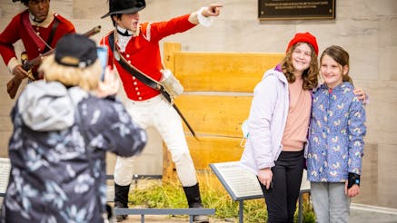 Two young visitors get their photo taken next to the Cost of Revolution tableau in the Rotunda.
