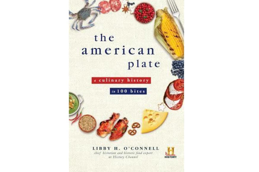 This image shows the book cover of The American Plate: A Culinary History in 100 Bites by Libby O'Connell. The title of the book is written in blue and red. Around the title are items of food forming the shape of a dish. From the top moving to the right is a blue shell grab, meat, anise, a bowl of red berries, a charred corn on the cob in the husk, Swiss cheese, small pretzels, two chicken wings, a bowl of grain, two small red peppers, and a bowl of green soup.