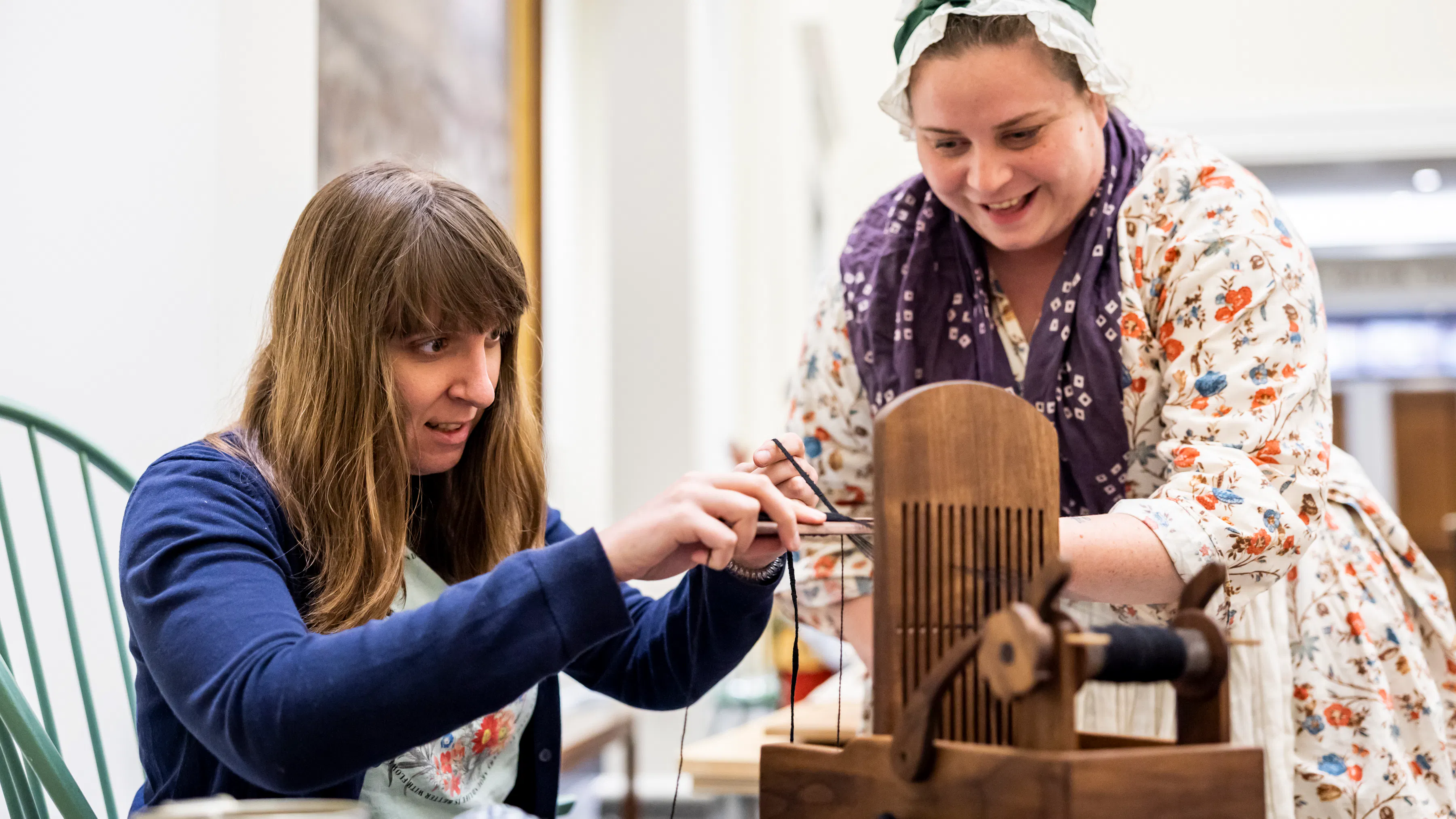 A guest interacts with a wooden artifact with the help of a costumed interpreter