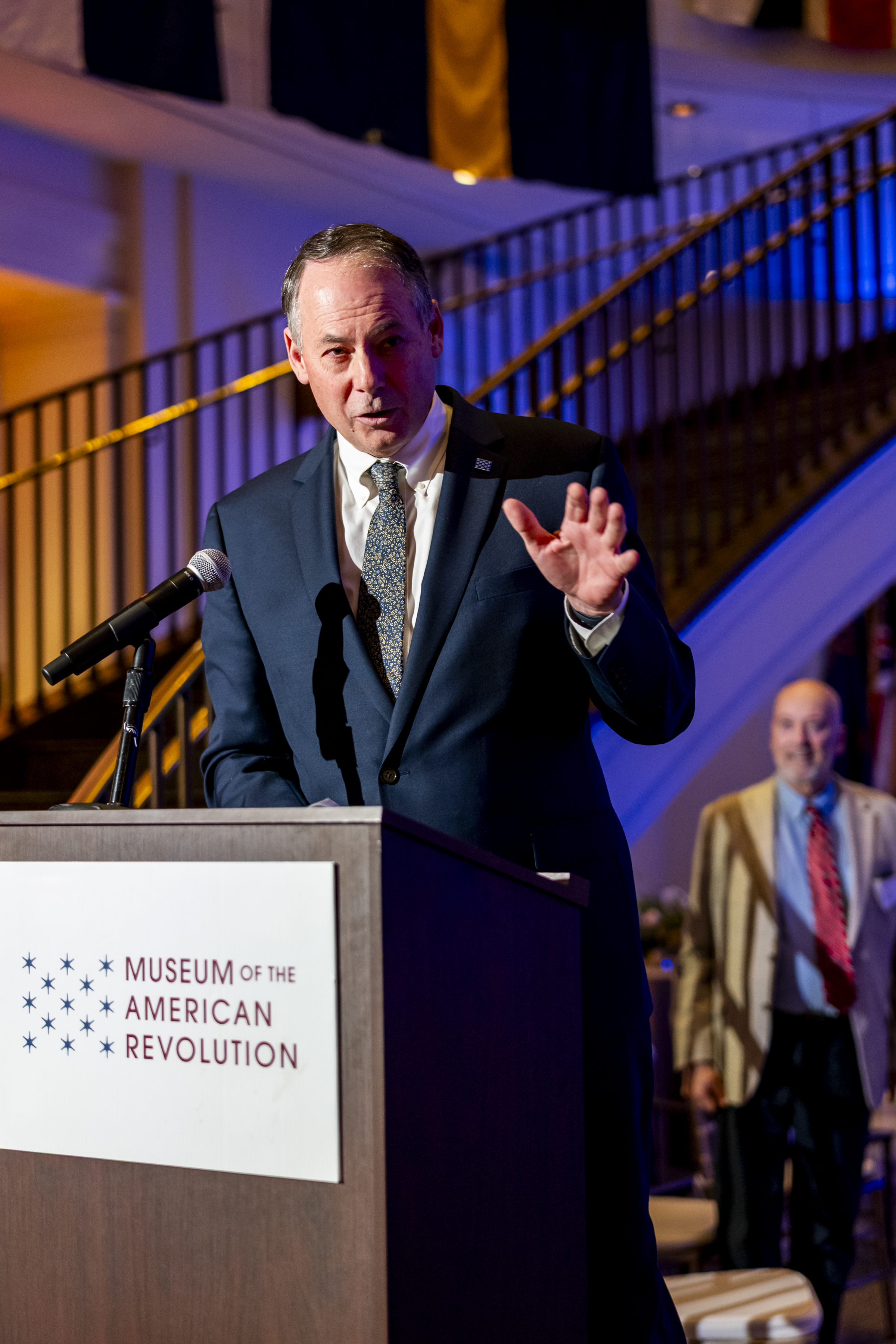 Museum President and CEO Scott Stephenson wearing navy blue suit and speaking at podium