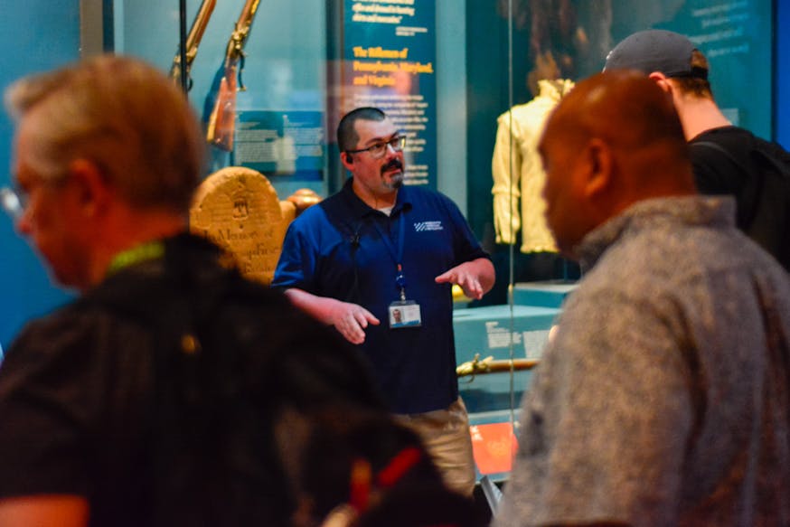 A Visitor Engagement Associate talks with a guest in the the Museum's core exhibition.