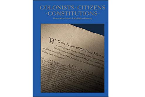 The image depicts Colonists Citizens Constitutions book cover by James Hrdlicka. It is a blue cover with a photo of the first few lines of the constitution. “We, the people of the United States,” is a visible.