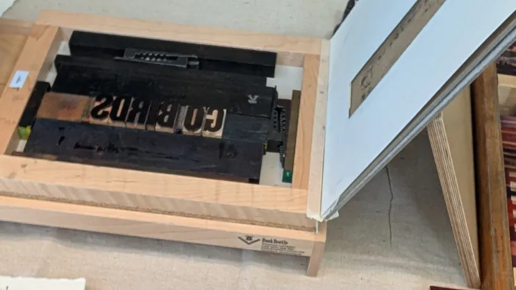 A tabletop printing press next to a typed card that says "We hold these truths to be self-evident."