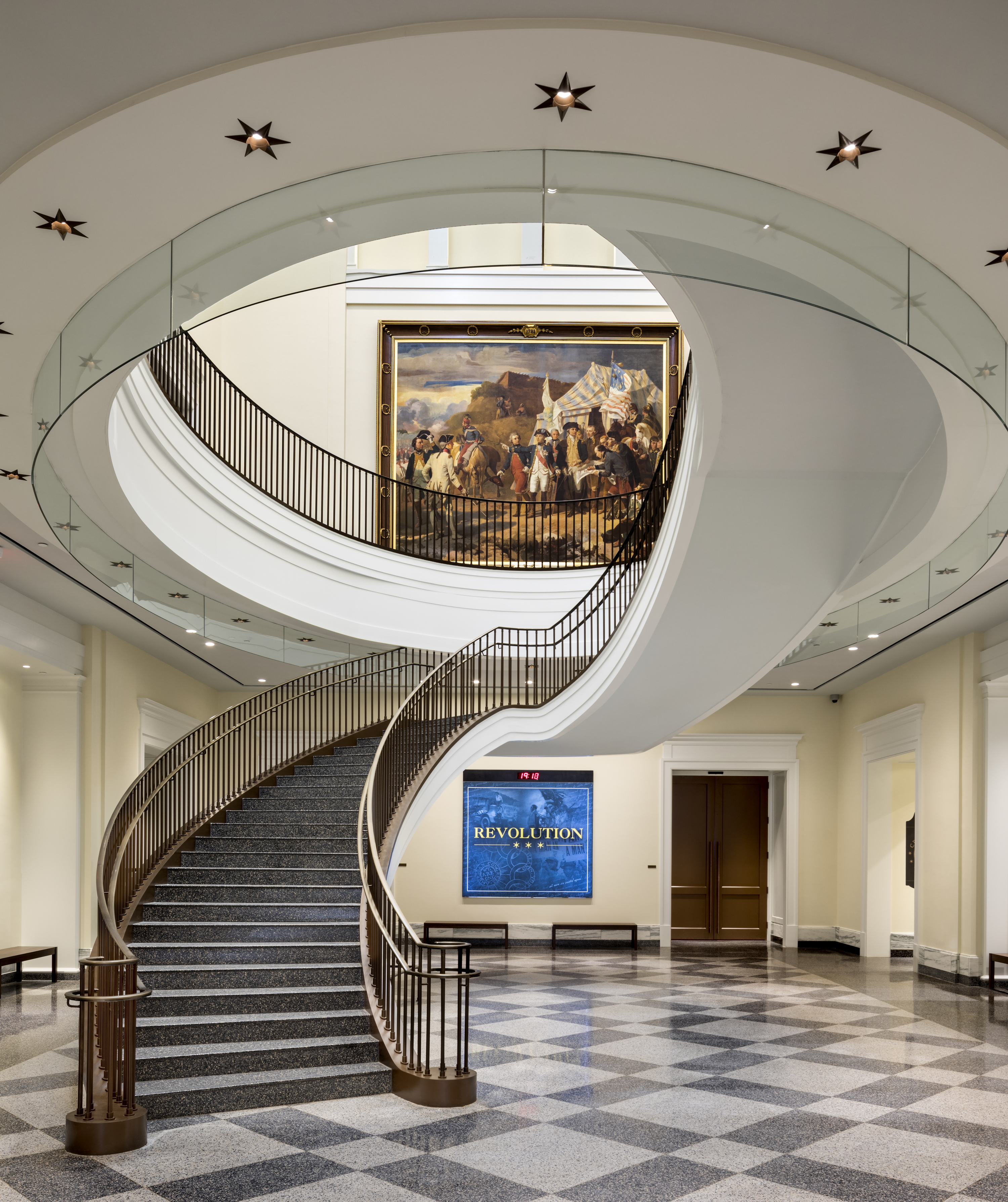 A large spiral staircase with a door and large sign that says Revolution behind it