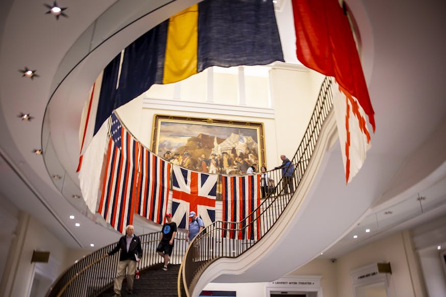 Image looking up the grand staircase at the replica flags created for the True Colours Flag Project around the railings with vistors walking up and down the stairs.
