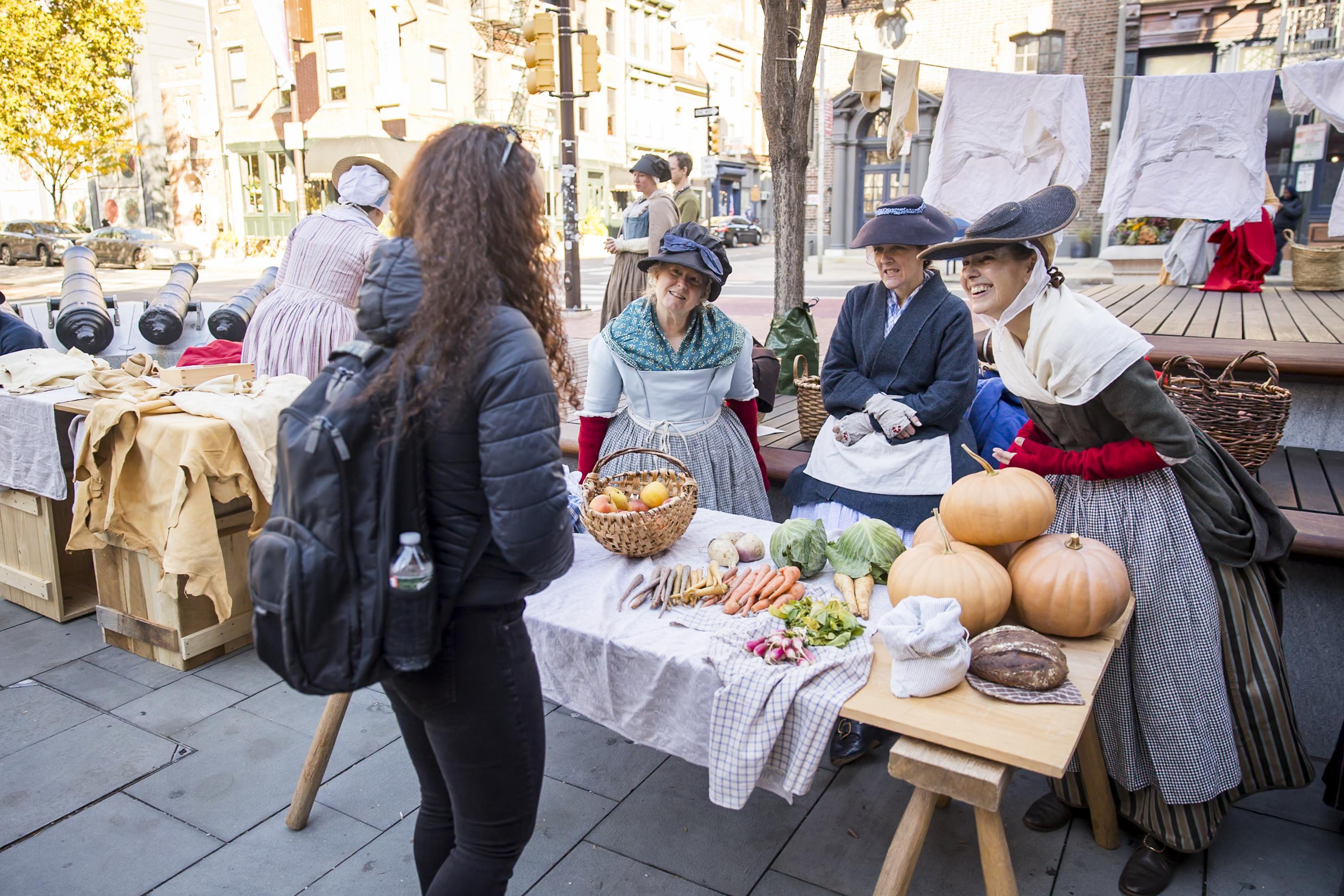 A person talks to three women in 18th century clothing