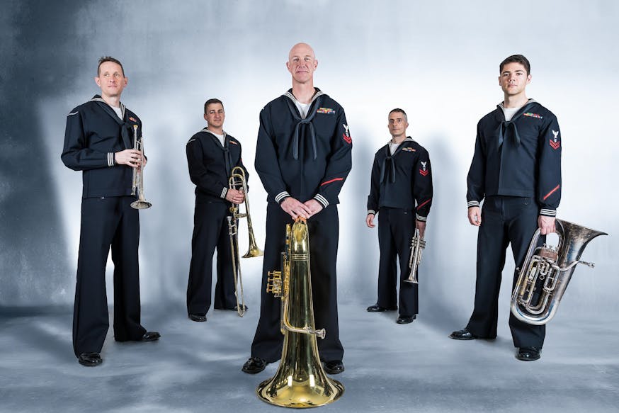 Members of the US Navy Band Northeast quintet holding their instruments while dressed in uniform.