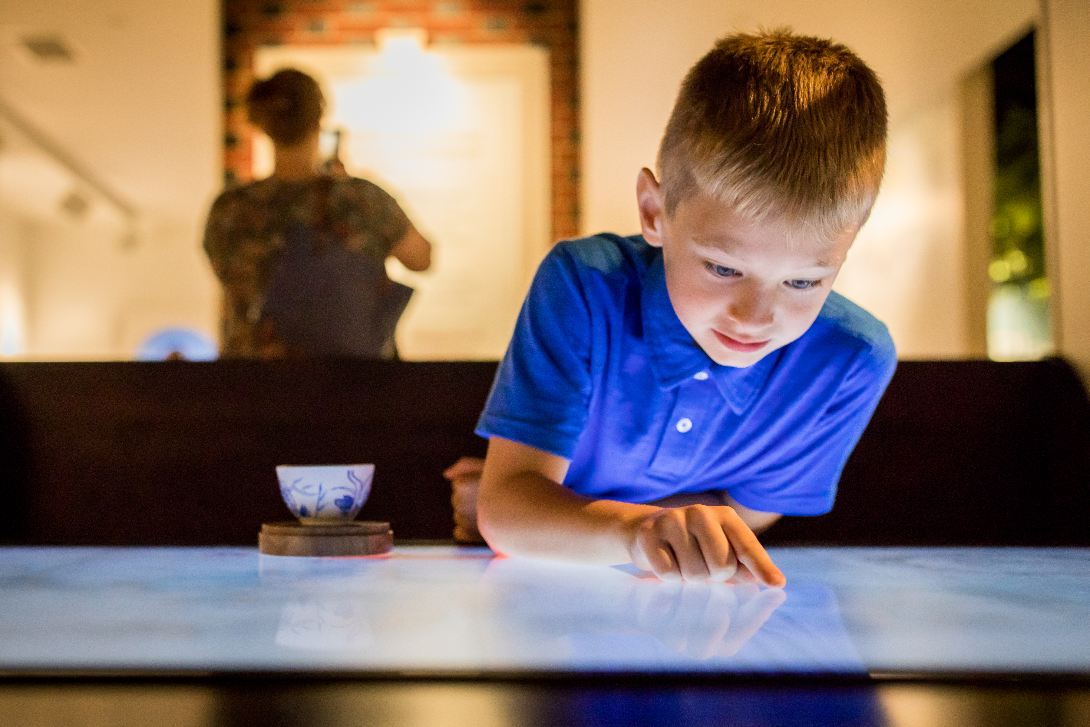 Kid in blue polo using digital table interactive
