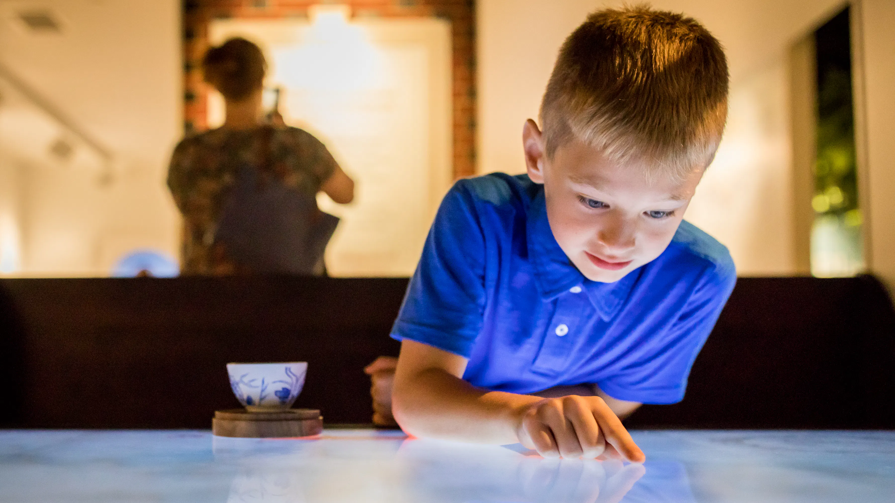Kid in blue polo using digital table interactive