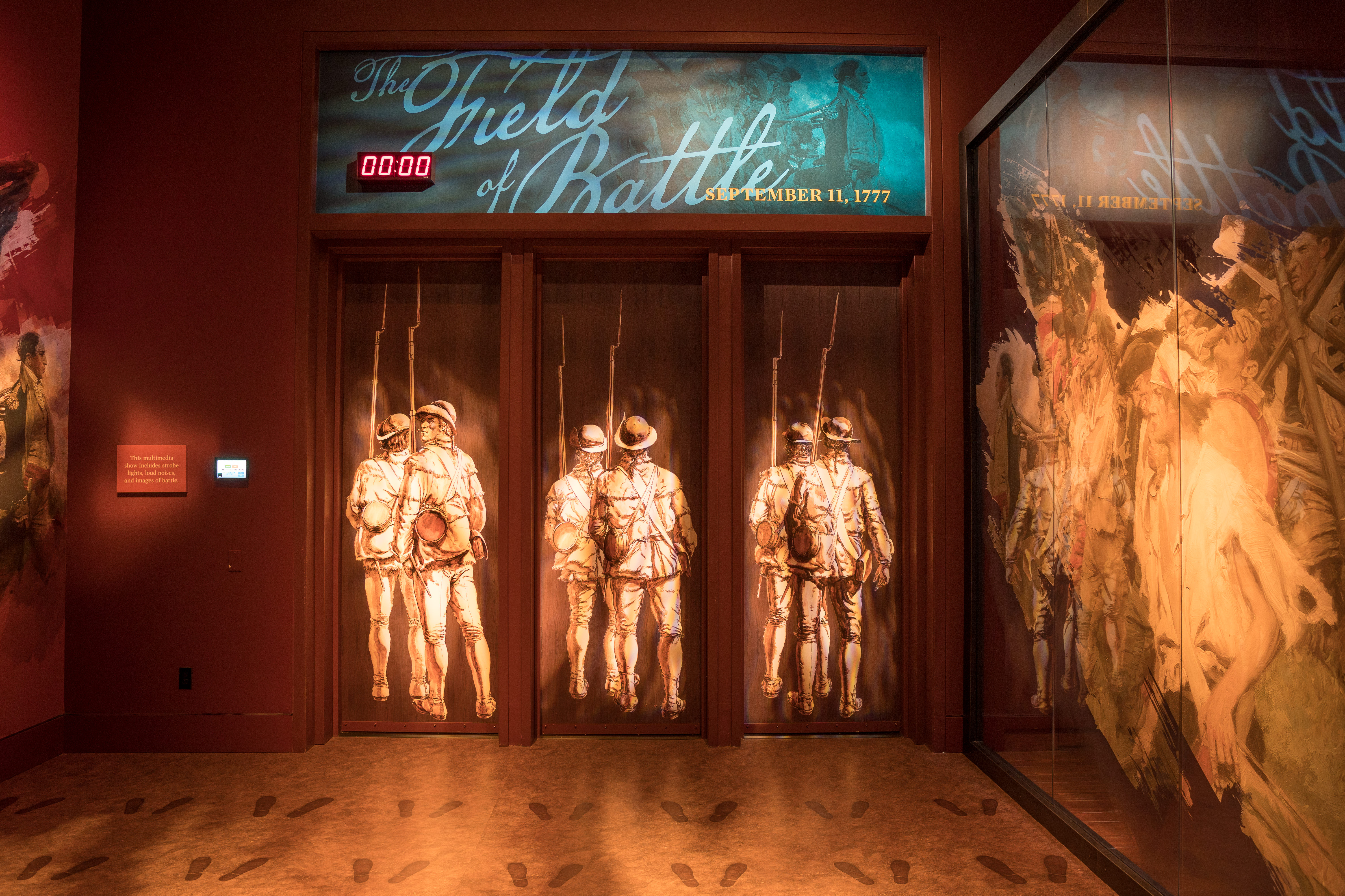 A set of doors with life-size illustrations of 18th century soldiers, under the title Field of Battle: September 11, 1777