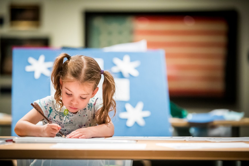 A young female visitor draws a picture. Behind her is a 13-star flag, which was part of the Museum's 2019 summer exhibition, A New Constellation.