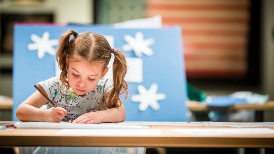 A young female visitor draws a picture. Behind her is a 13-star flag, which was part of the Museum's 2019 summer exhibition, A New Constellation.