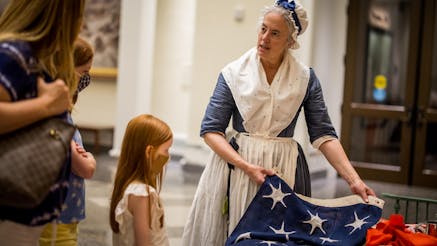 True Colours maker Ruth Hodges shows a young girl a reproduction American flag she sewed for the project.