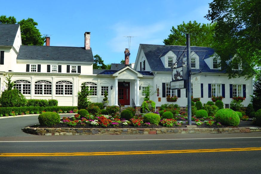 This image shows the long white 18th century inn with black shutters and details.