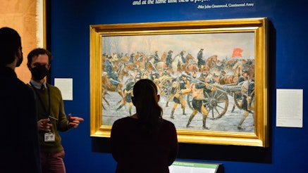 Two visitors view paintings in the Museum's Liberty exhibit with a Museum staff member..