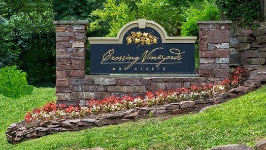 This image shows the stone and black sign at the entrance of Crossing Vineyard and Winery.