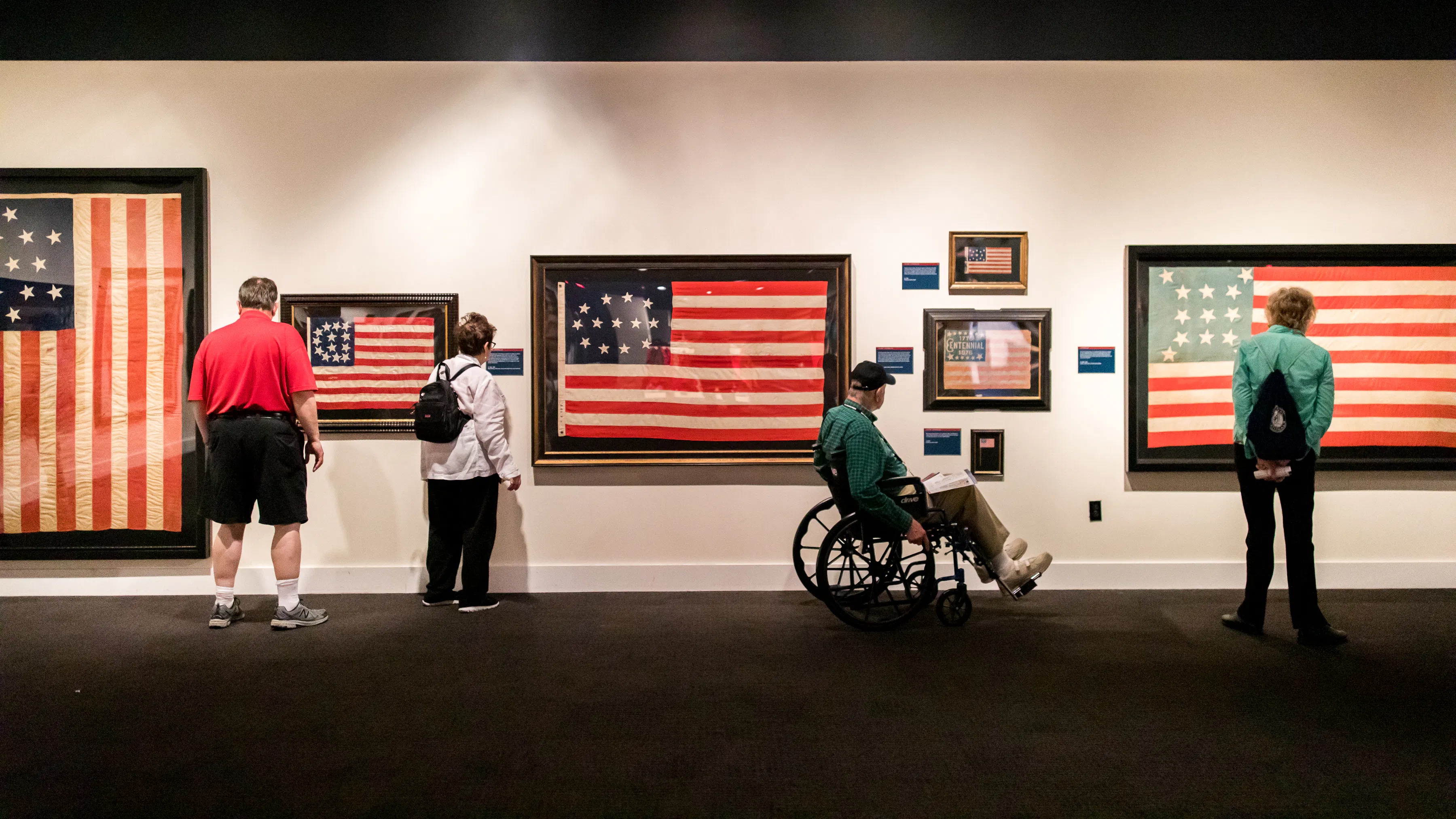 Museum patrons looking at various Revolutionary-era American flags in the "Banners of Liberty" Museum exhibit