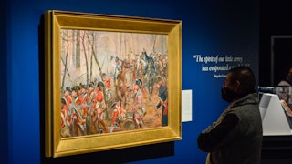 A Museum staff member views a painting in the Liberty exhibit