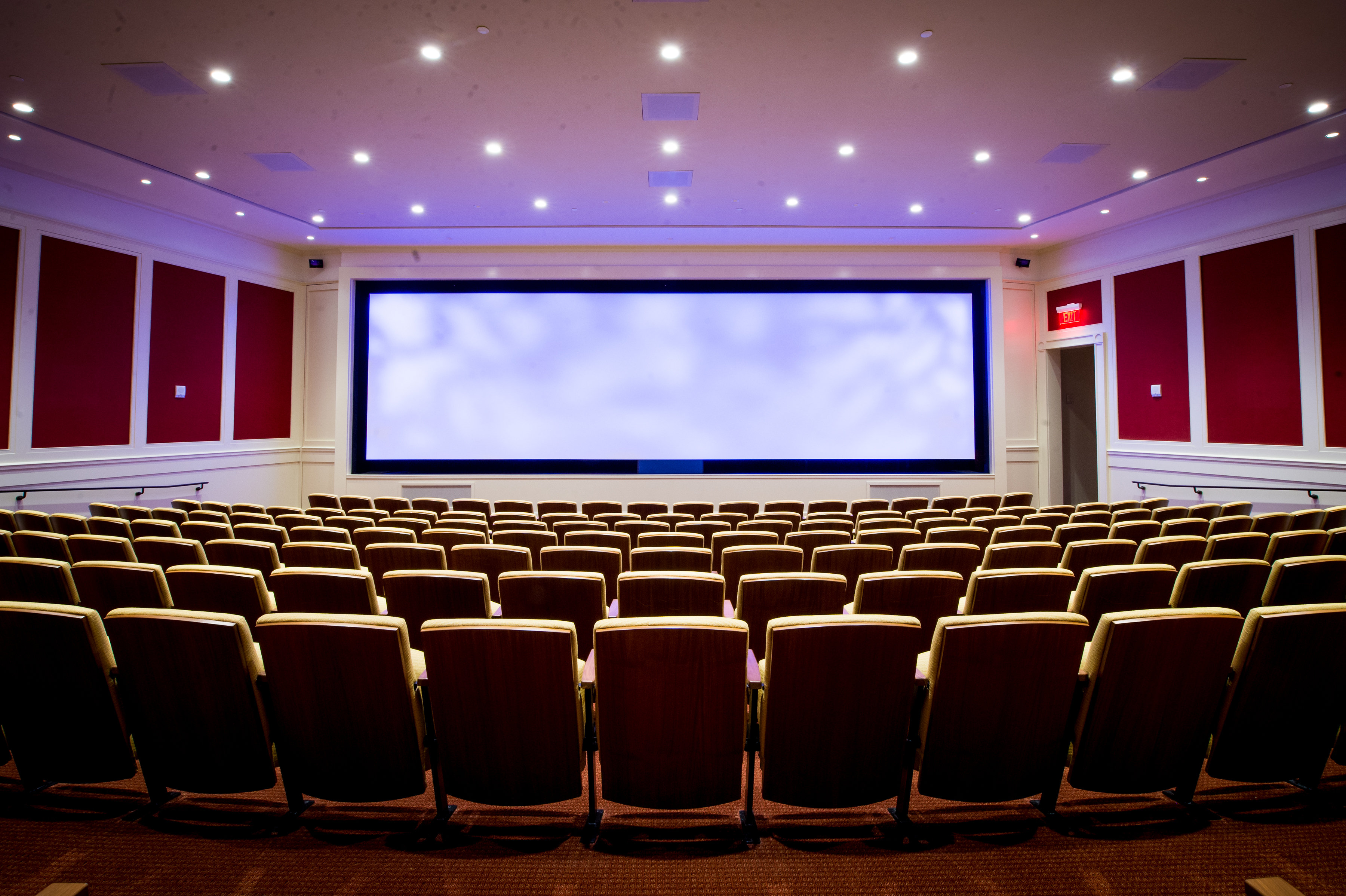 Rows of seats in front of a large screen showing a cloud-like pattern