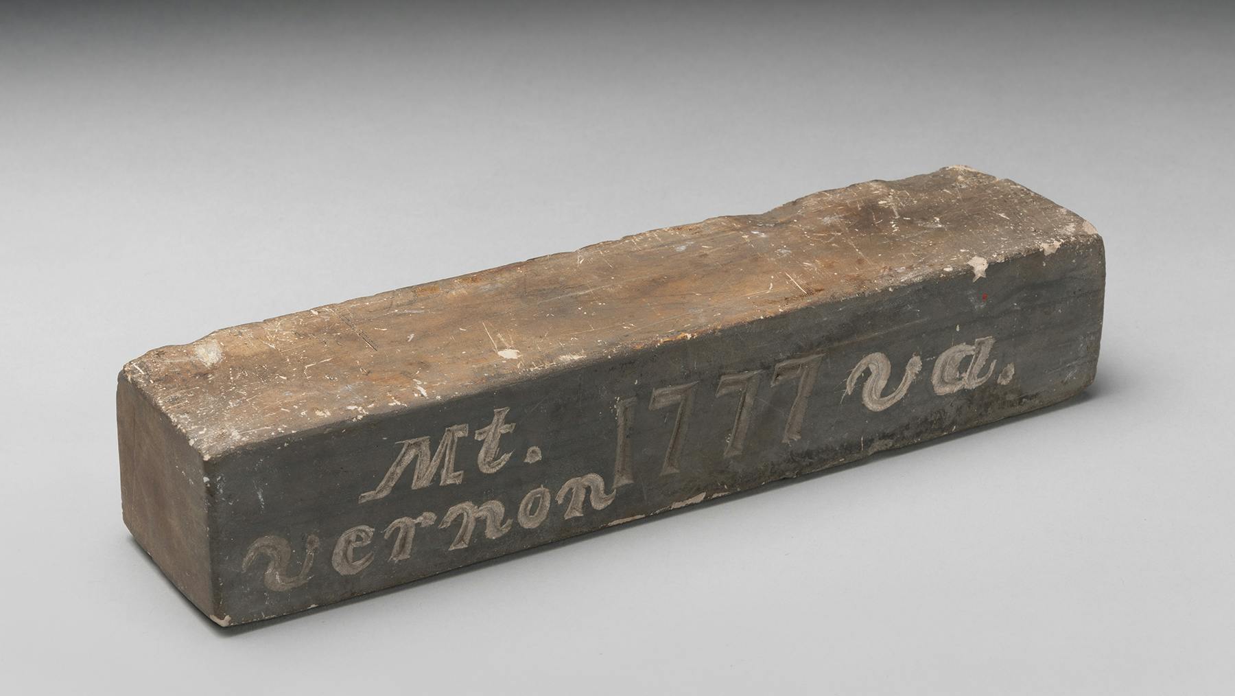 A brick-shaped grayish brown stone with the words Mt. Vernon 1777 Va. etched on one side.