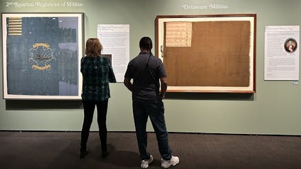 Two people look at framed flags in the Banners of Liberty exhibit