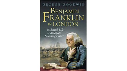 This image depicts the book cover of Benjamin Franklin in London: The British Life of America’s Founding Father by George Goodwin. Benjamin is pictured seated at a table with a red tablecloth and reading. He is wearing a blue jacket with gold trim. He is holding the paper in his left hand, while his right hand is resting on his chin. He is wearing gold eyeglasses.
