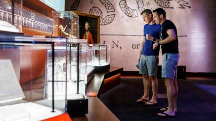 Two guests stand in front of lit glass cases