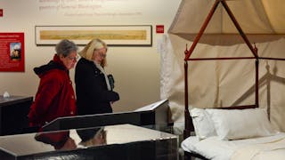 Two members view the wooden structure of Washington's camp bed on display in the Witness to Revolution exhibit.