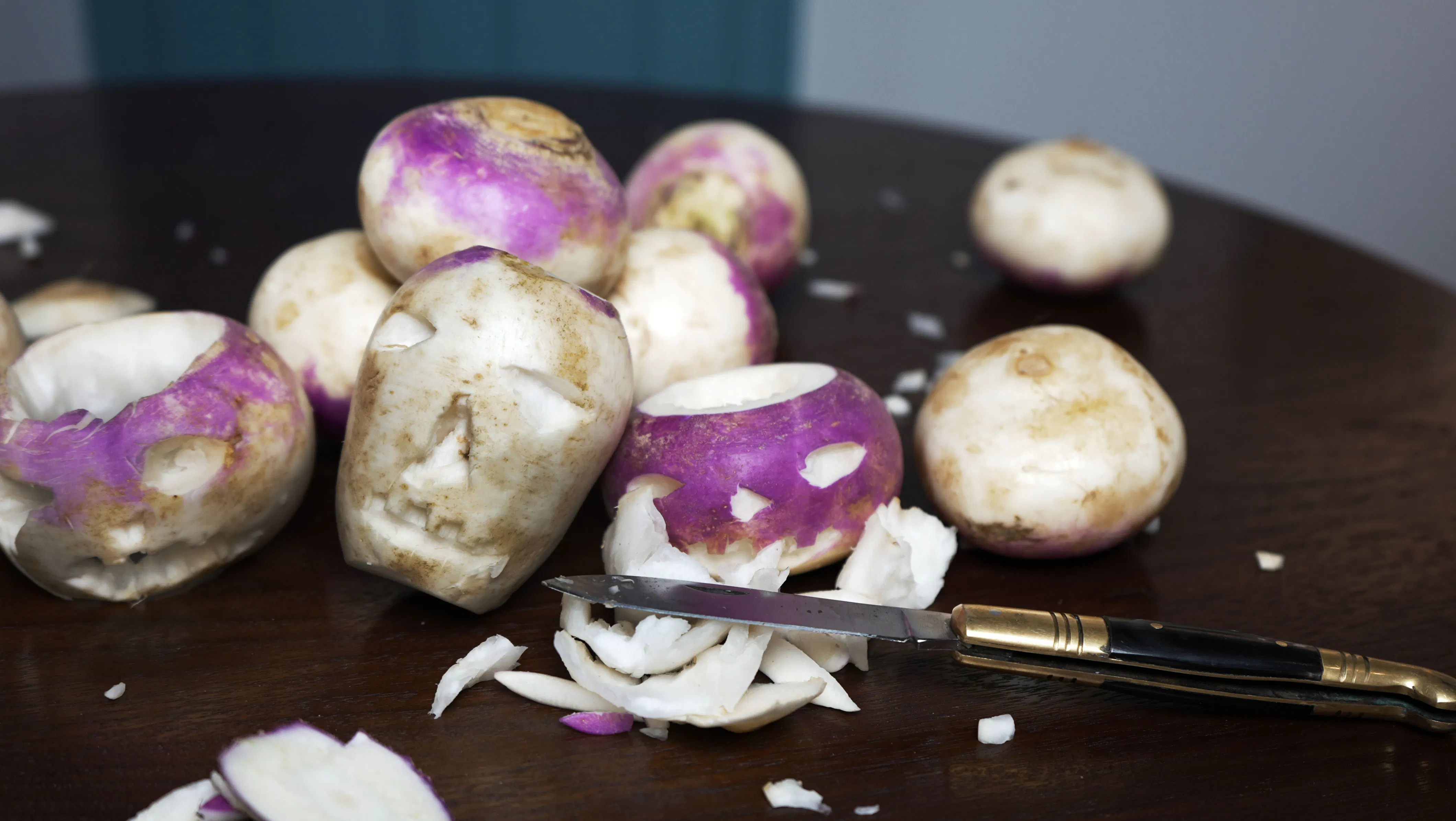 This image shows turnips with their off white color and purplish exterior carved into faces in an 18th century style.