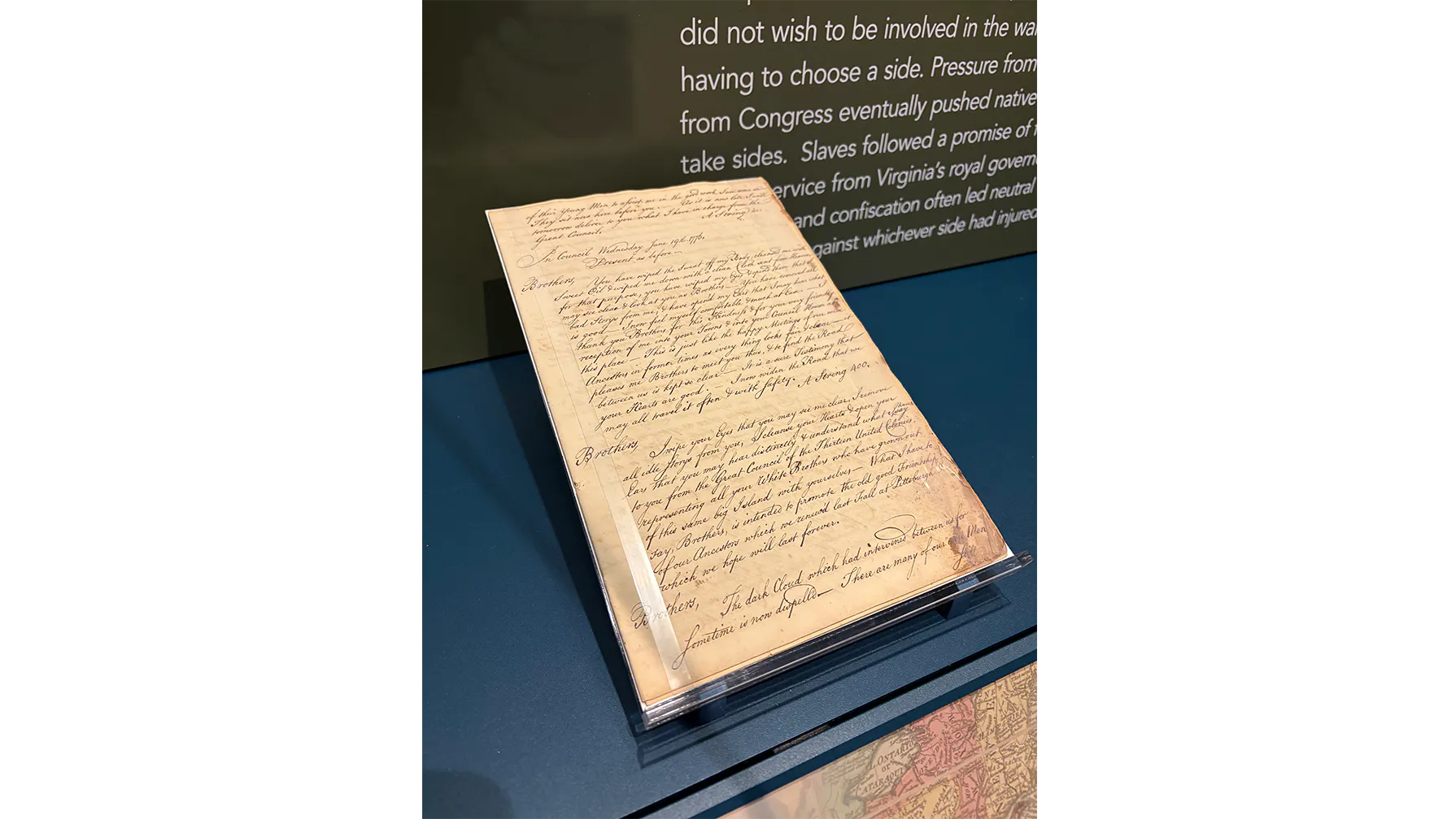 A handwritten document propped up in a case with text behind it