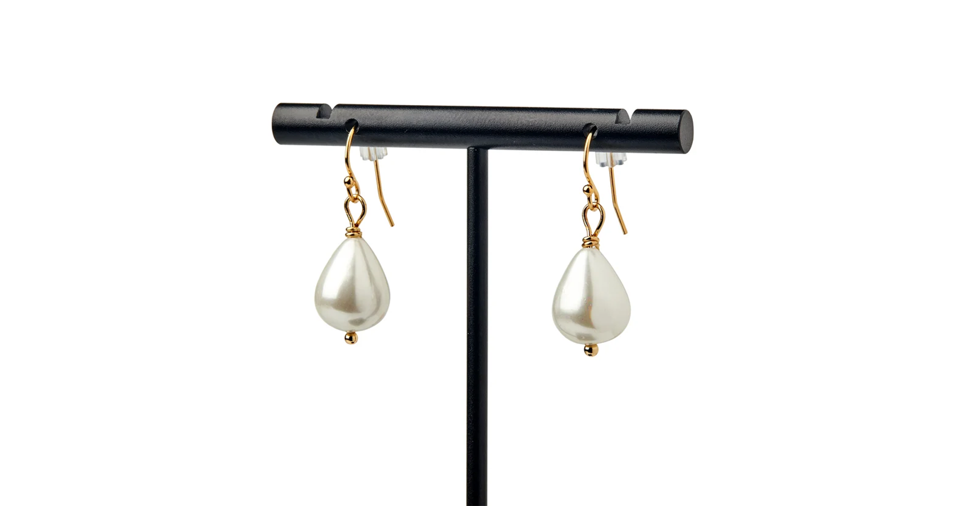 A pair of gold and pearl earrings on a black stand