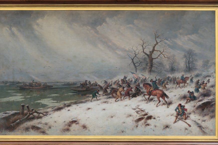 This image shows a painting depicting George Washington Crossing the Delaware. It is displayed in a brown frame with a gold interior. The painting shows Washington and his soldiers on the shores of the river. Some are still on land and some boats are already on the water. It is a snowy, gray day.