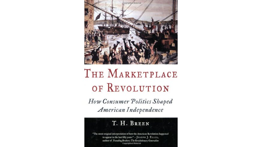 This image depicts the book cover of The Marketplace of Revolution: How Consumer Politics Shaped American Independence by T.H. Breen. The bottom of the book cover is black, and the author’s name is written in white text. The middle of the cover is white, and the text is written in red and black. And the top of the cover is an image of ships docking and people on the docks.