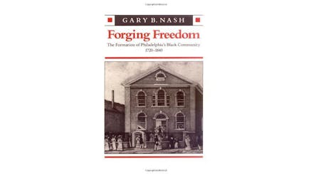 This image depicts the book cover of Forging Freedom: The Formation of Philadelphia’s Black Community 1720-1840 by Gary Nash. It is a white cover with a sepia toned image of a Revolutionary era building with a door and windows on either side and three windows on the second floor. The top of the building is triangular. There are people walking down the street in front of the building.