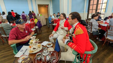 A Museum Member talks to two costumed living historians dressed as British redcoats at the member teatime at Occupied Philadelphia.