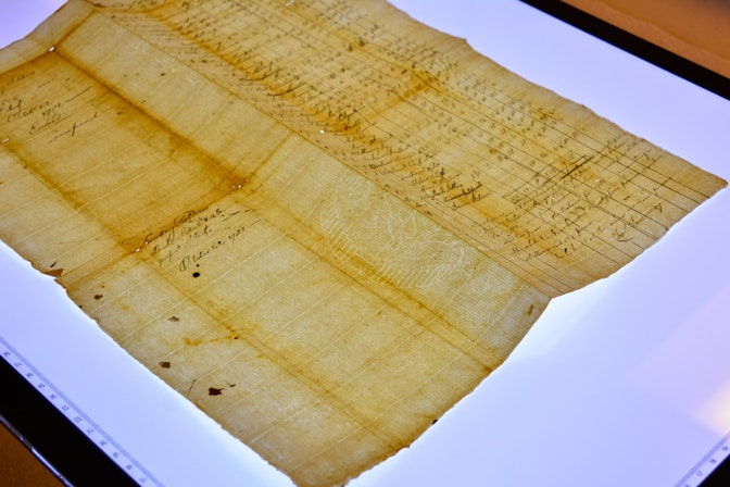 A document lays on a light board to show a water mark on the paper.