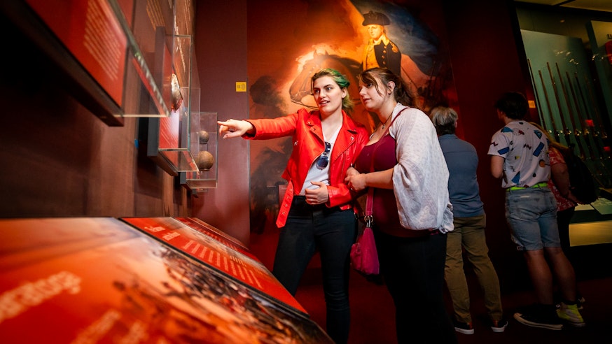 A woman points out an object to another woman at the Museum of the American Revolution.